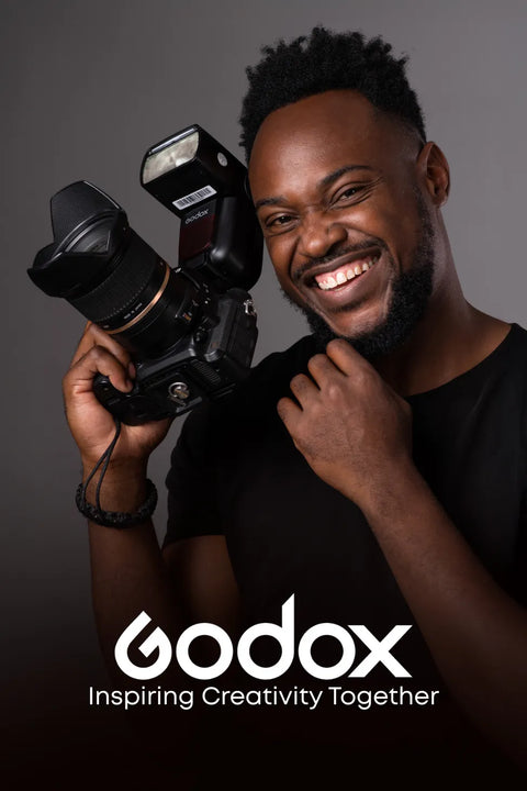 Man holding a camera with Godox branding on a dark background