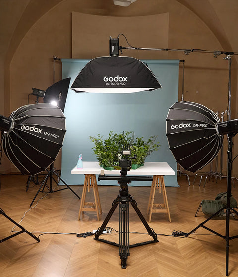 Photography studio setup with Godox lighting equipment and a table with plants.